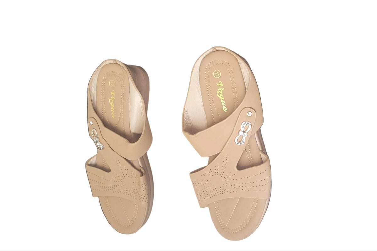 A pair of tan double-strap slide sandals with clear rhinestone embellishments on the straps, shown on a dark wood floor.