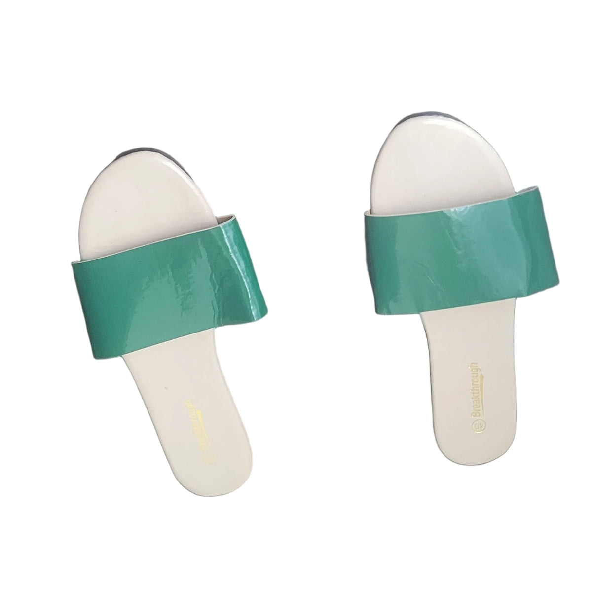 A pair of green and white slide sandals placed on a dark wood floor.
