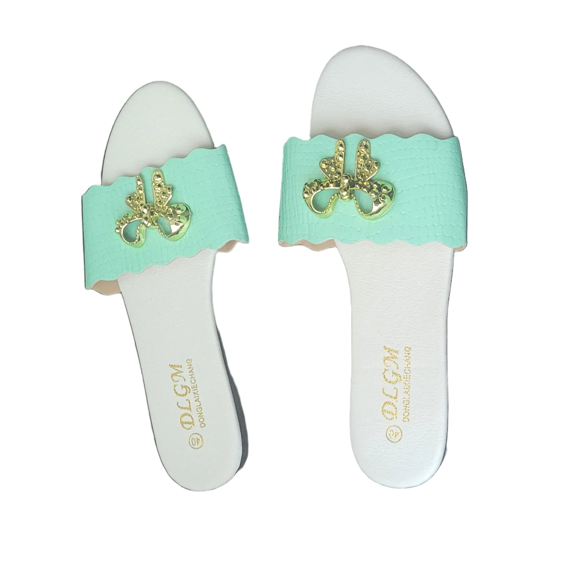 A pair of white slide sandals with mint green straps featuring a gold-tone metal filigree detail, resting on a dark wood floor. The brand name 'POTTE' is printed in gold on the footbed.