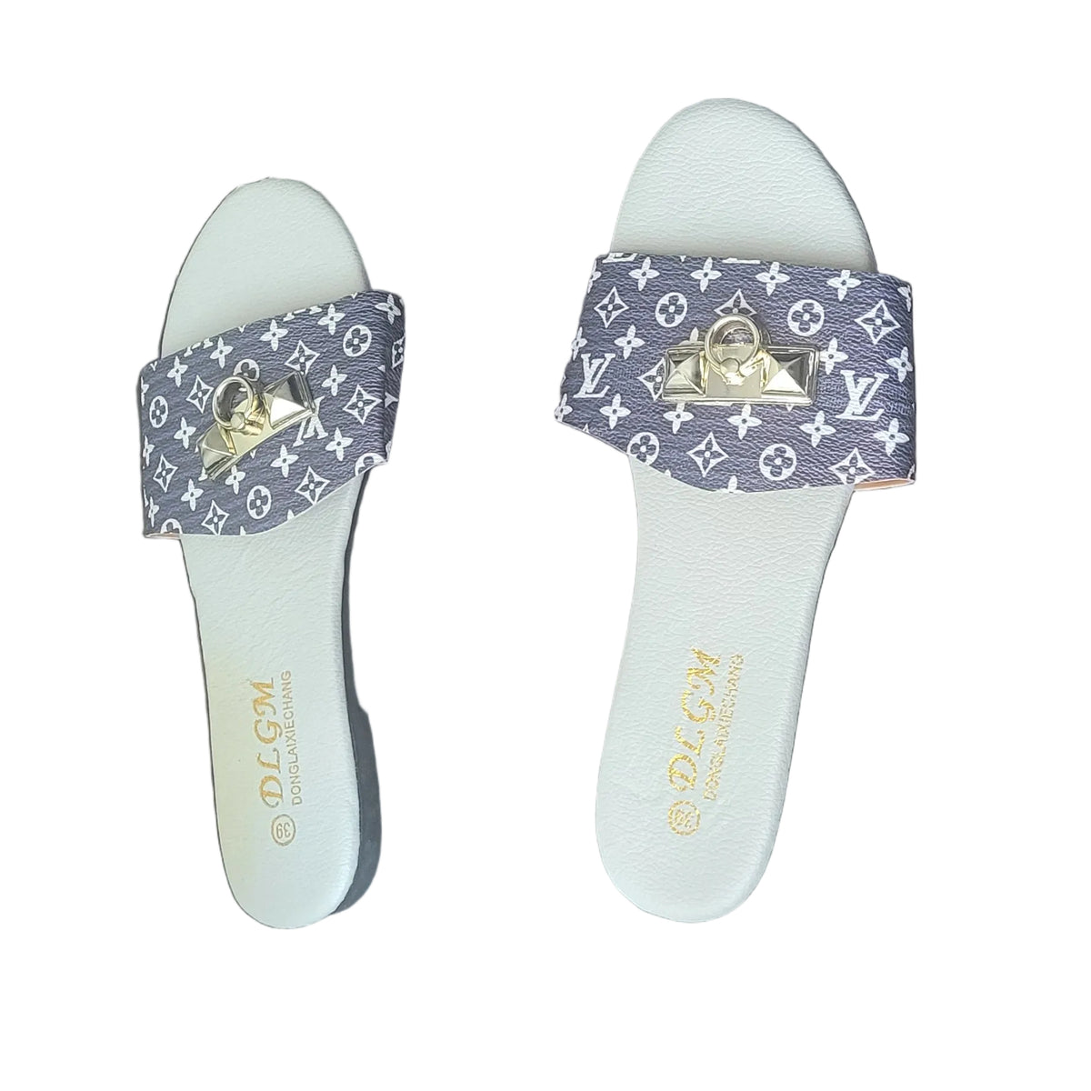 A pair of white slide sandals with blue and white monogram-patterned straps and gold-tone hardware, displayed on a dark wood floor.