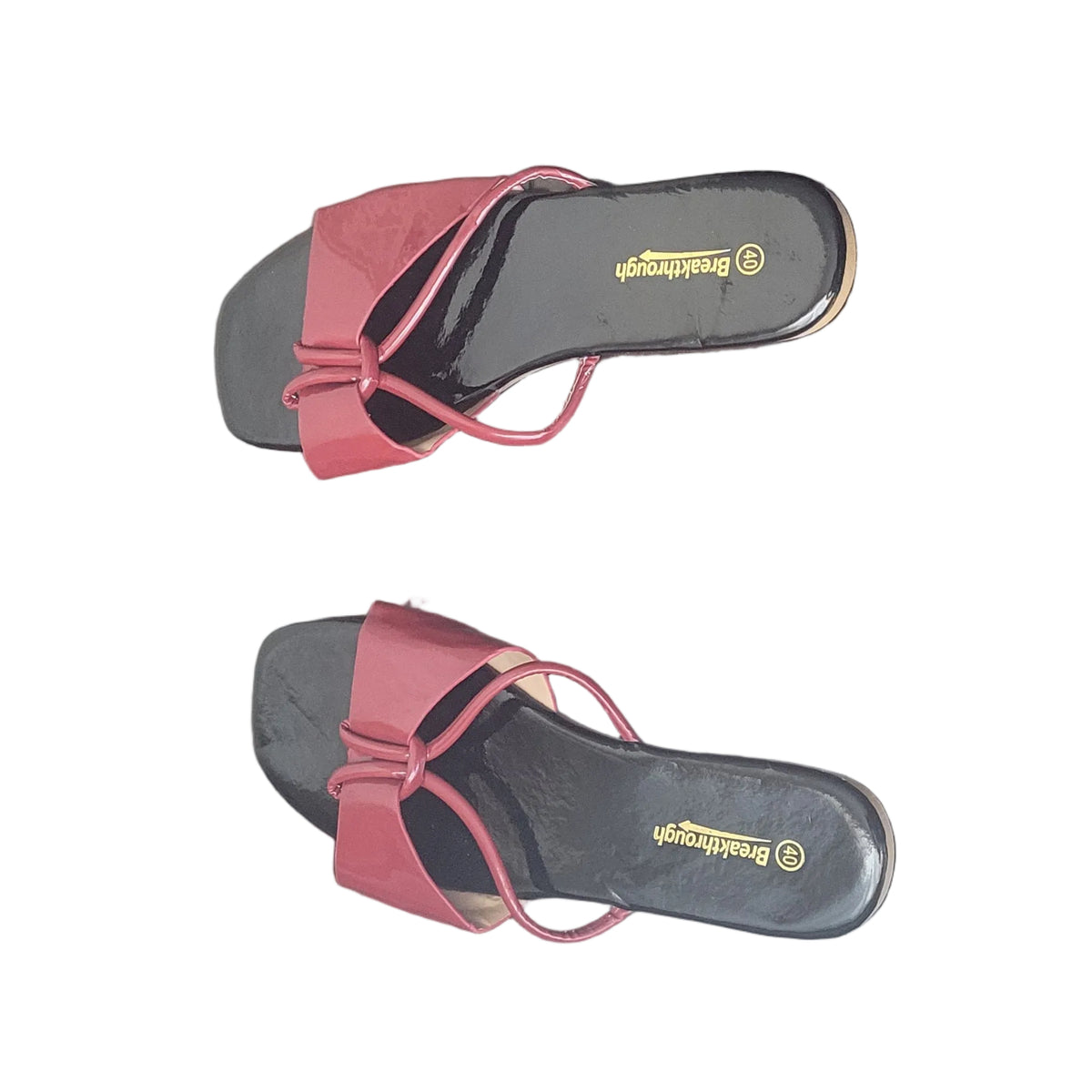 A pair of women's red slide sandals with black footbeds and gold branding, placed on a dark wood floor.