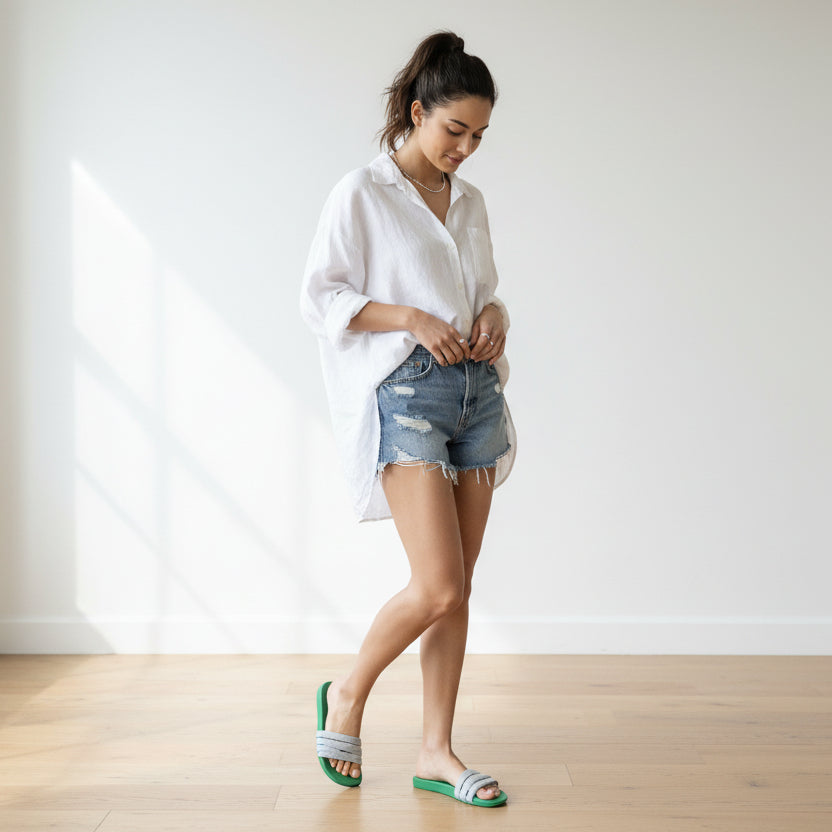 A pair of green orthopedic footbeds with white and blue striped straps, laid flat on a dark wood floor.