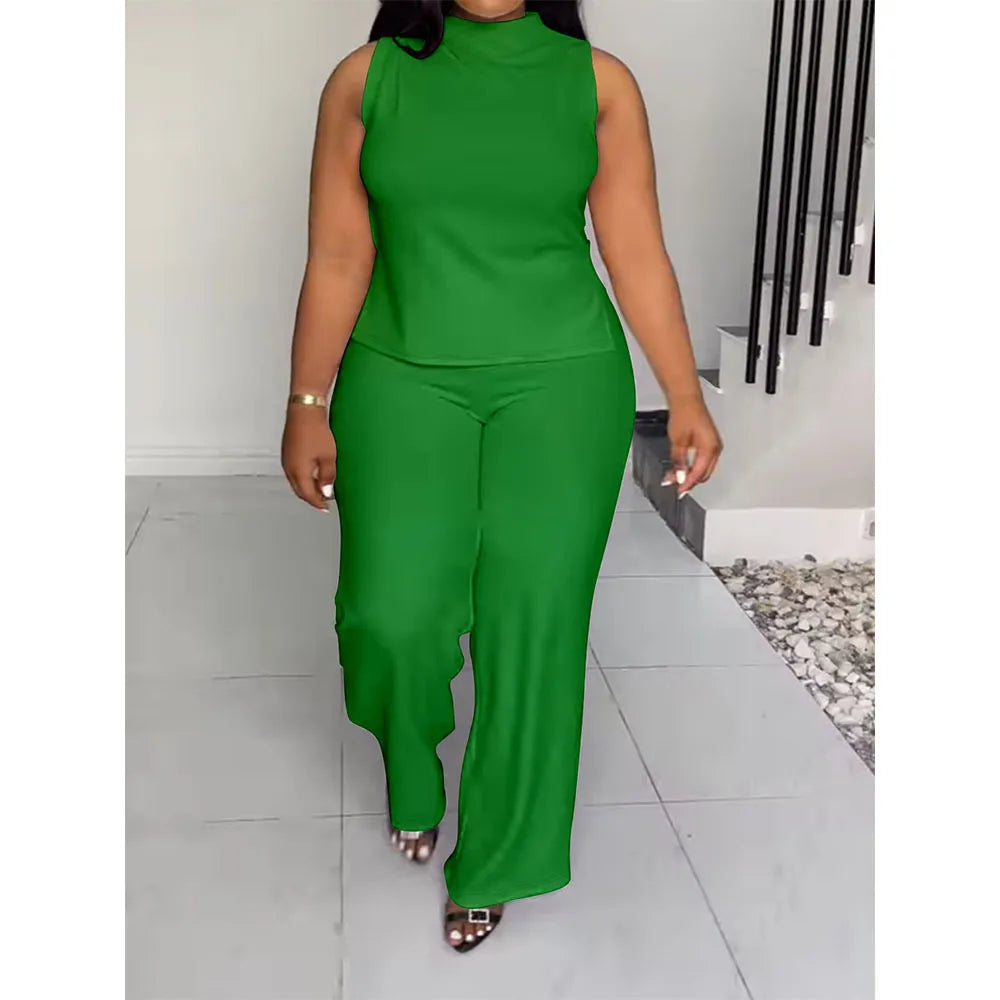 A woman modeling a bright green sleeveless mock-neck top and matching wide-leg pants set, walking indoors on a light tiled floor.