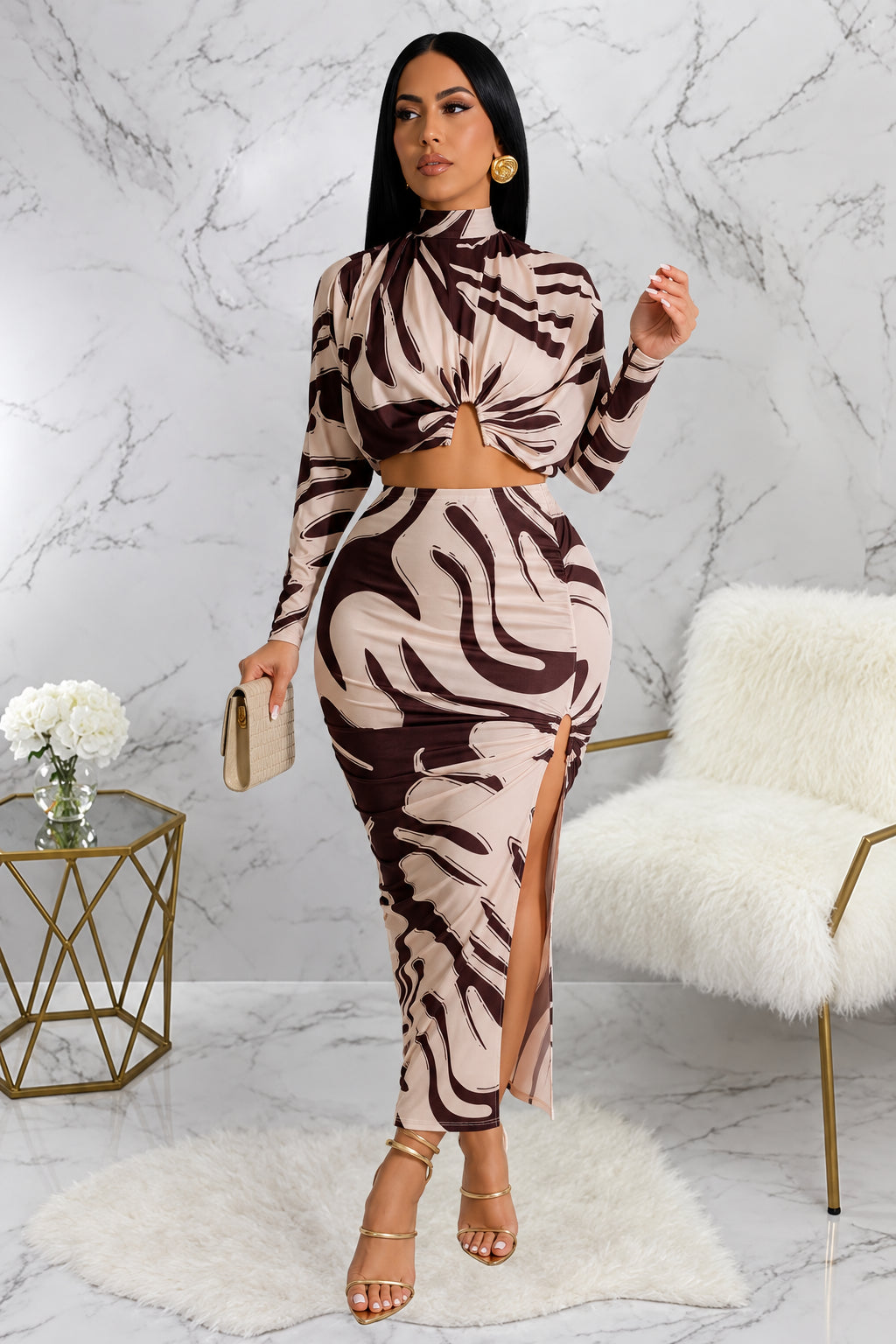 Woman in a zebra print outfit standing in a stylish room with marble walls and a white fur chair.
