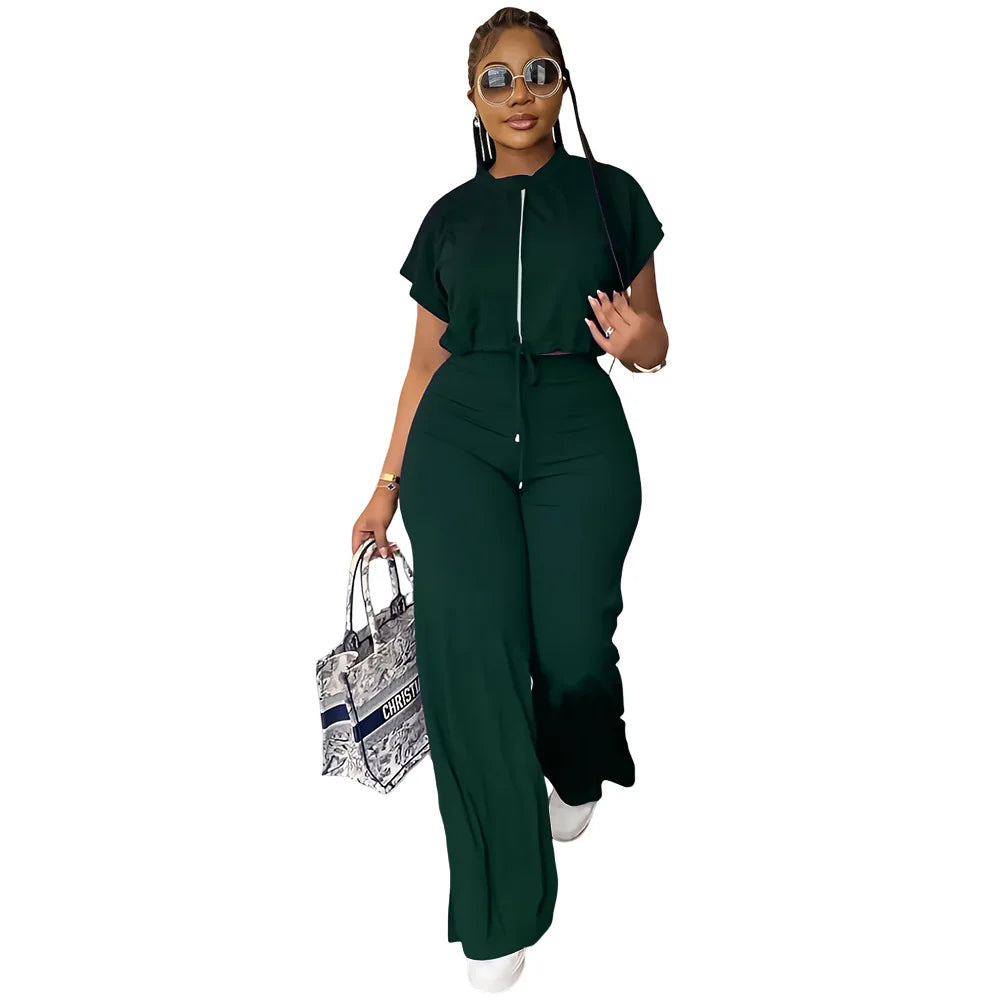Woman wearing a green jumpsuit holding a patterned handbag on a white background