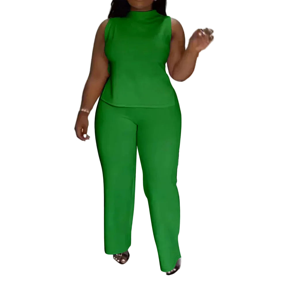 A woman modeling a bright green sleeveless mock-neck top and matching wide-leg pants set, standing indoors on a light tiled floor near a staircase. The brand name 'CM.