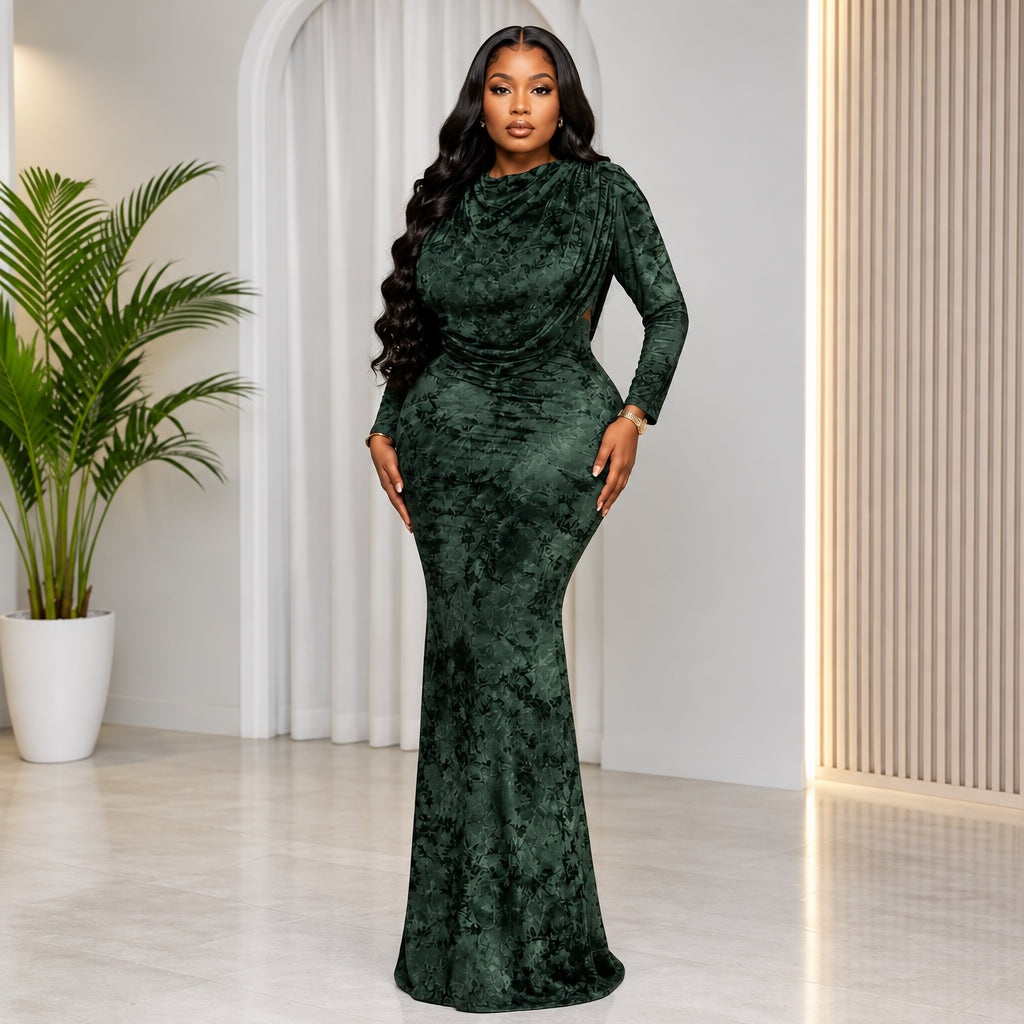 A woman modeling a dark green velvet long-sleeve mermaid gown in a bright indoor setting. The brand name 'CM.