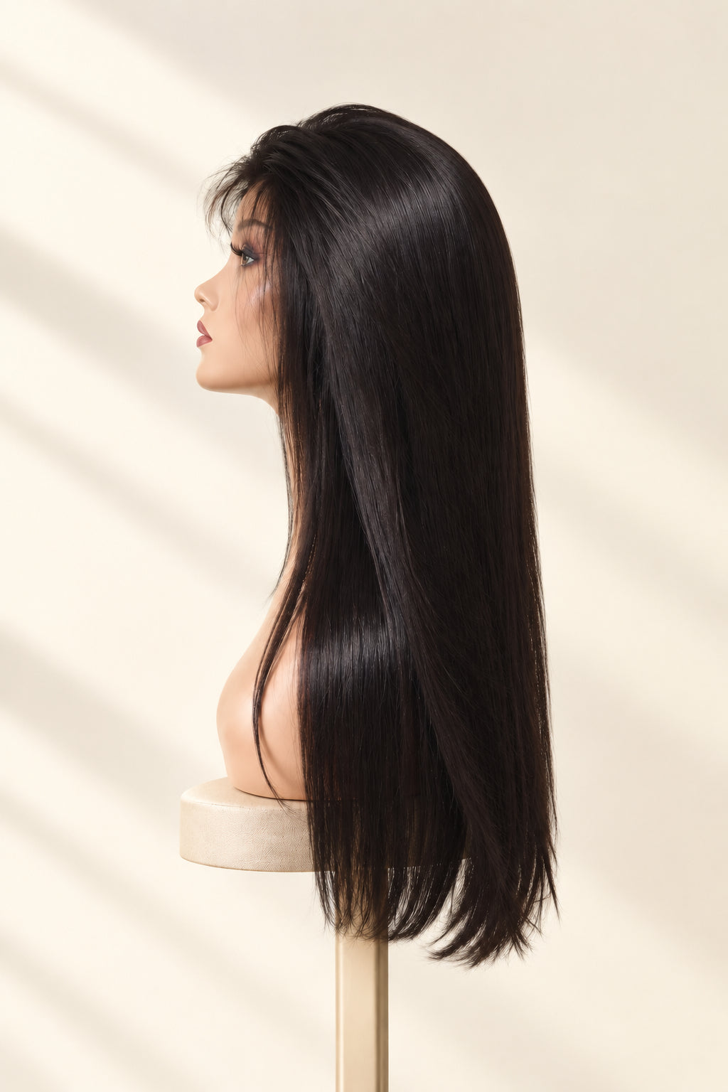 A long, dark brown wig with side-swept bangs displayed on a mannequin head stand against a white textured wall.