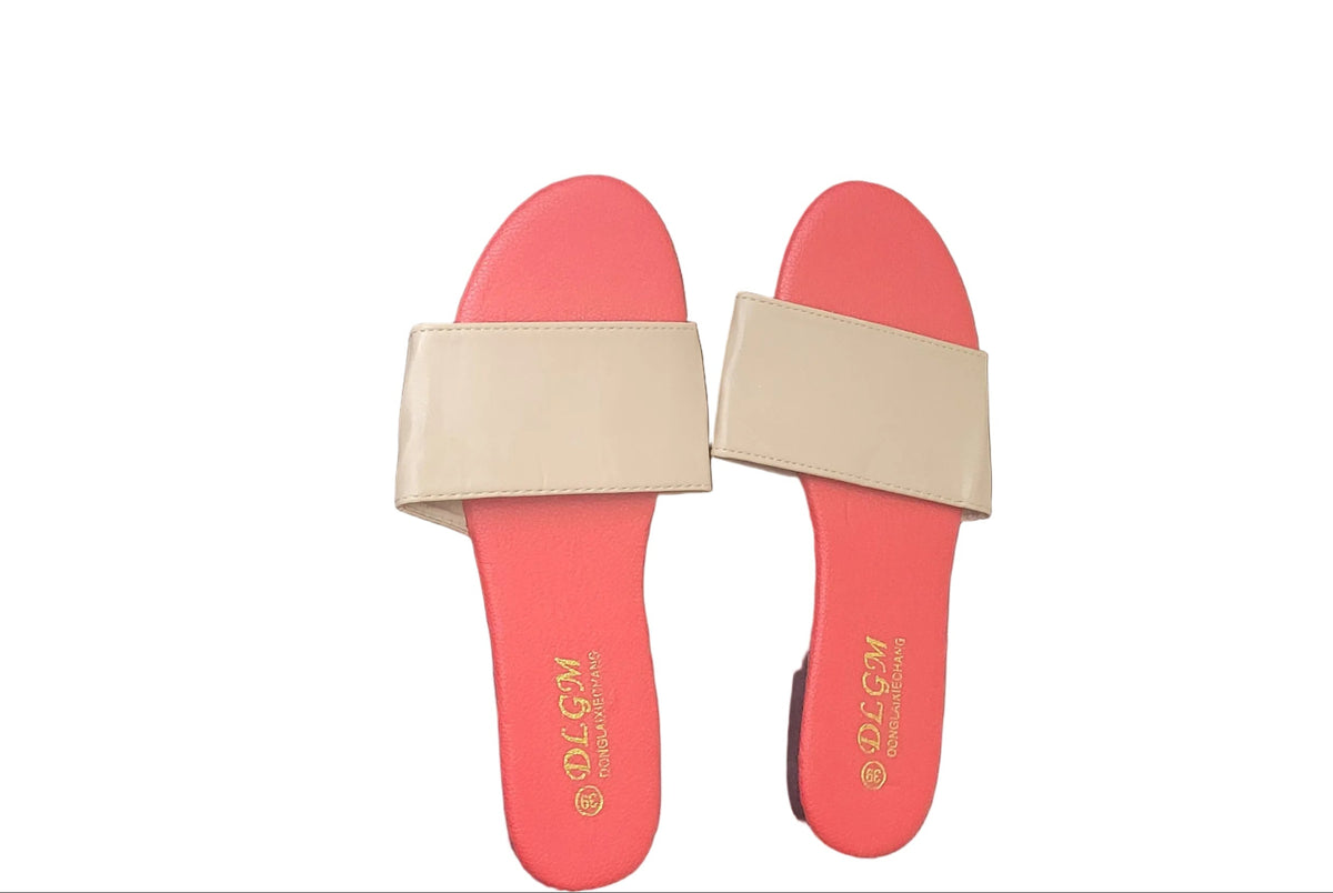 A pair of coral pink slide sandals with beige straps, placed on a dark wood floor. The brand name 'SOLIAN' is printed in gold on the footbed.