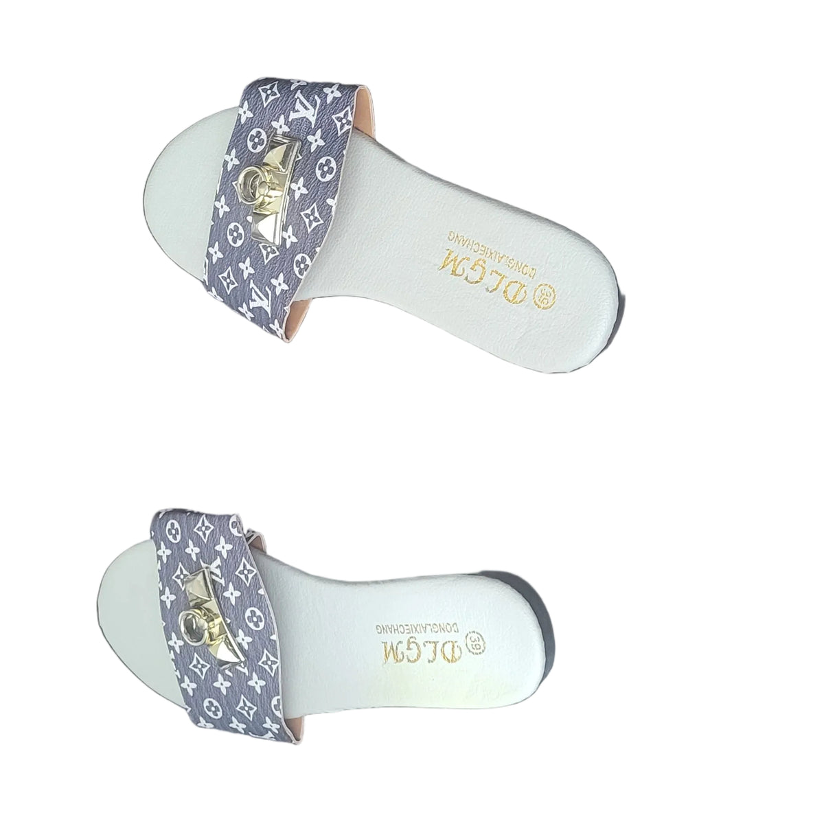 A pair of white Gucci slide sandals with a purple and gold monogram pattern strap, placed on a dark wood floor.
