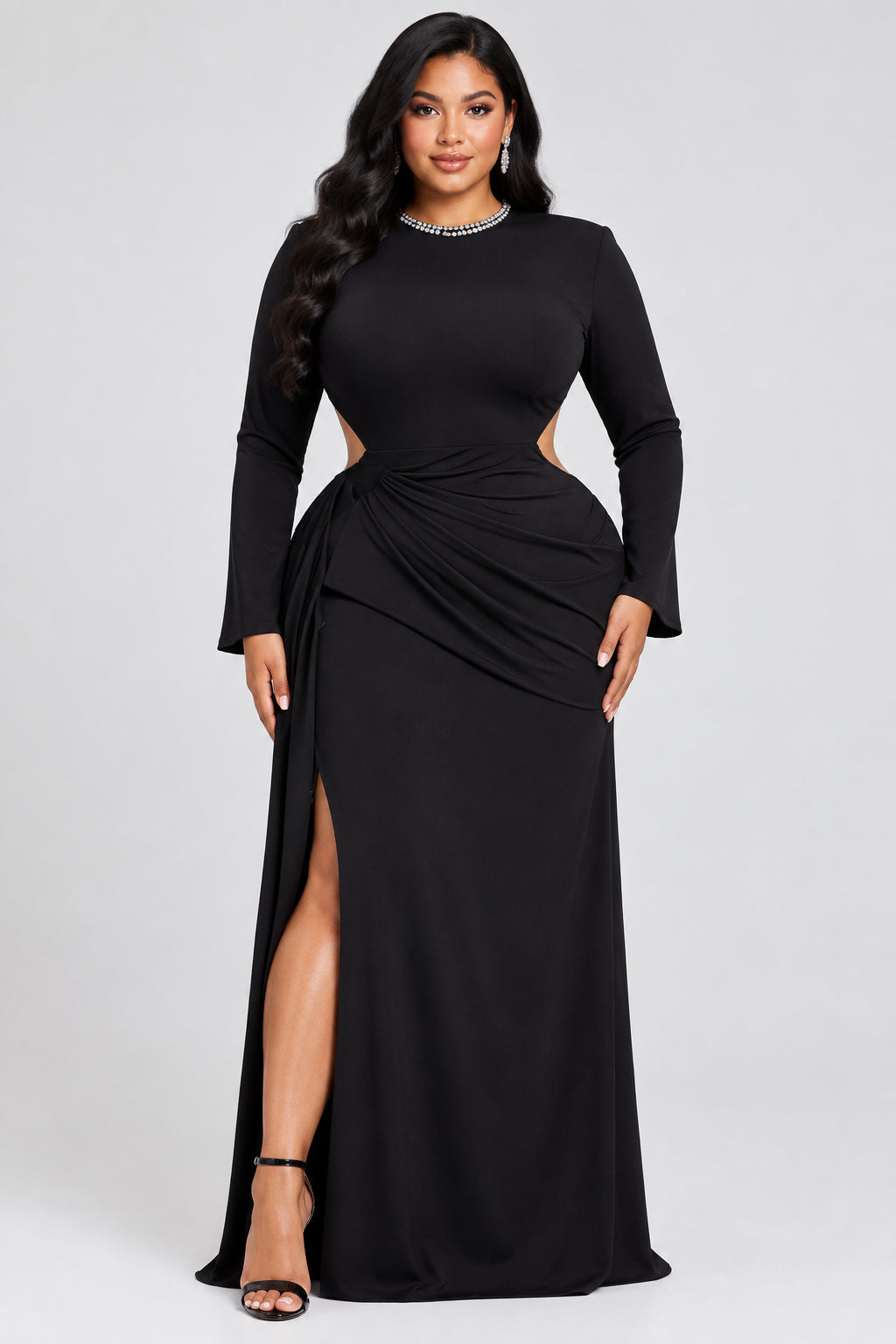 A black long-sleeve maxi dress displayed on a mannequin in an indoor boutique setting. The dress features a fitted bodice, draped side detail, and a high neckline.