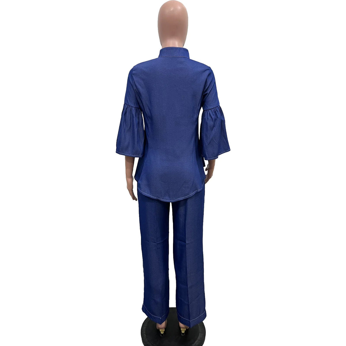 A mannequin wearing a blue two-piece outfit consisting of a short-sleeve collared top with flared three-quarter sleeves and matching wide-leg pants, shown from the back on a white background with the brand name CM.YAYA in the top left corner.