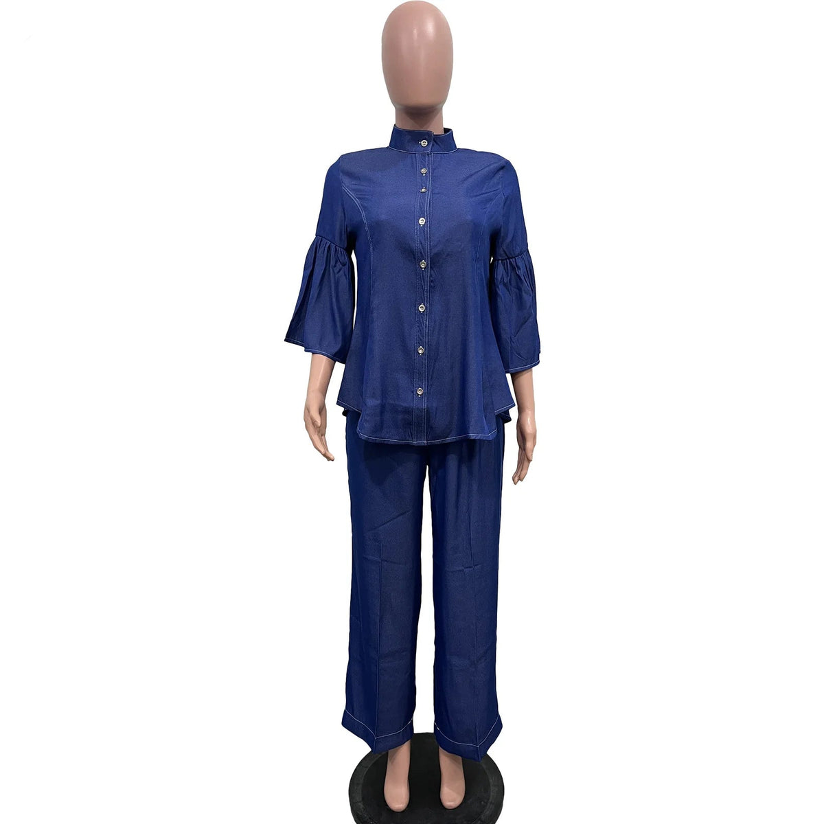 A two-piece women's outfit in dark blue denim-like fabric, consisting of a long-sleeve button-front top with ruffled sleeves and matching wide-leg pants, displayed on a mannequin. The brand name 'CM.