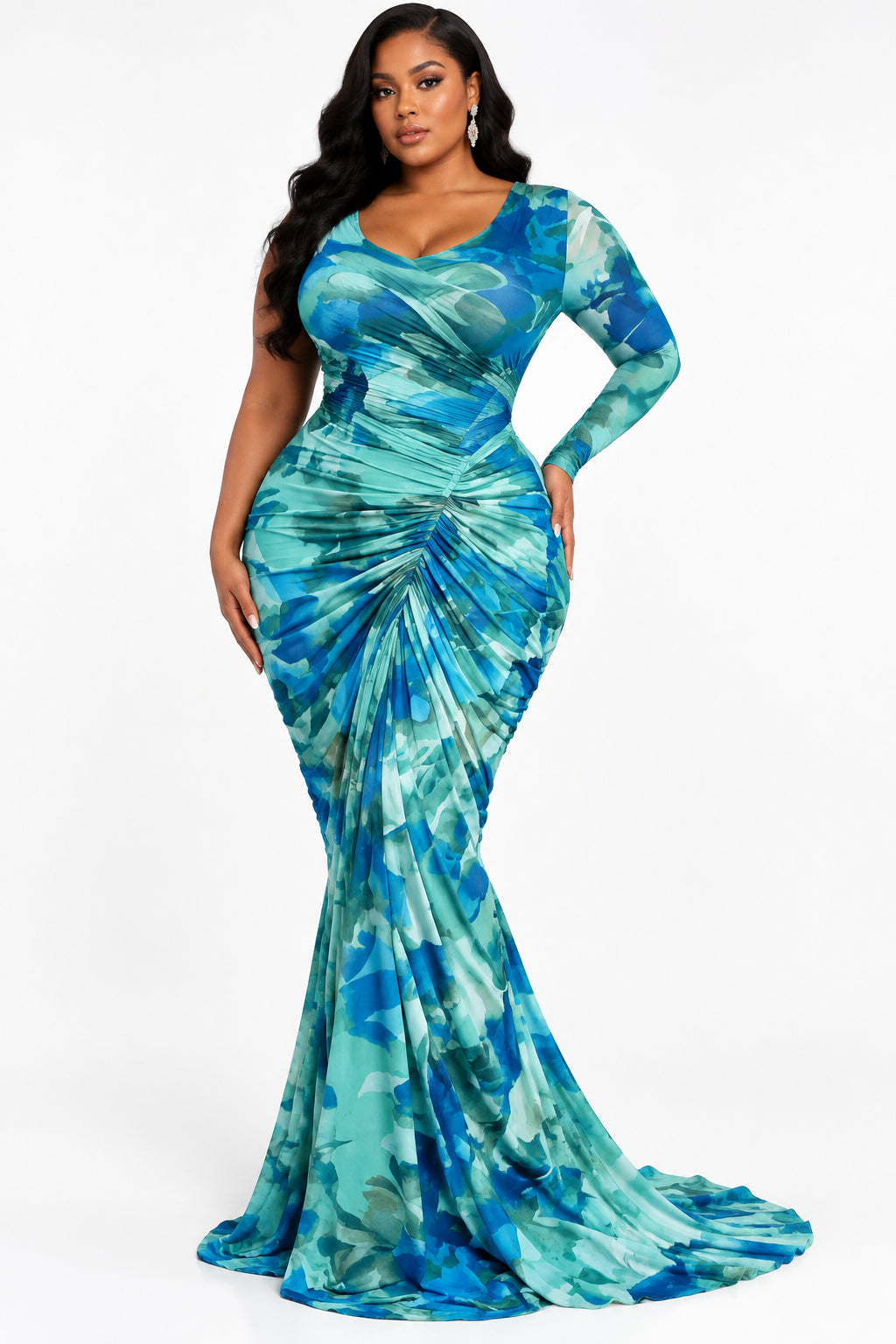 A long-sleeve floor-length gown displayed on a mannequin in an indoor showroom. The dress has a blue and teal tie-dye pattern with a gathered ruched bodice and a long draped train.