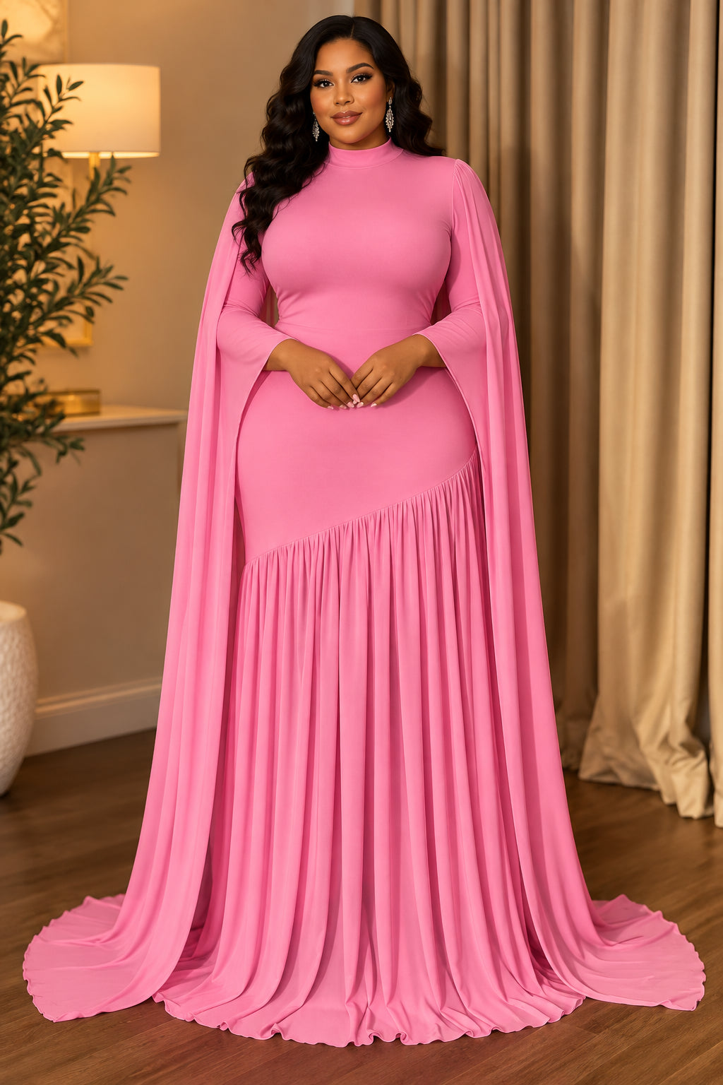 A bright pink floor-length gown displayed on a mannequin in an indoor room with curtains and wood flooring. The dress has long draped sleeves, a fitted bodice, and a flared pleated skirt with a train.