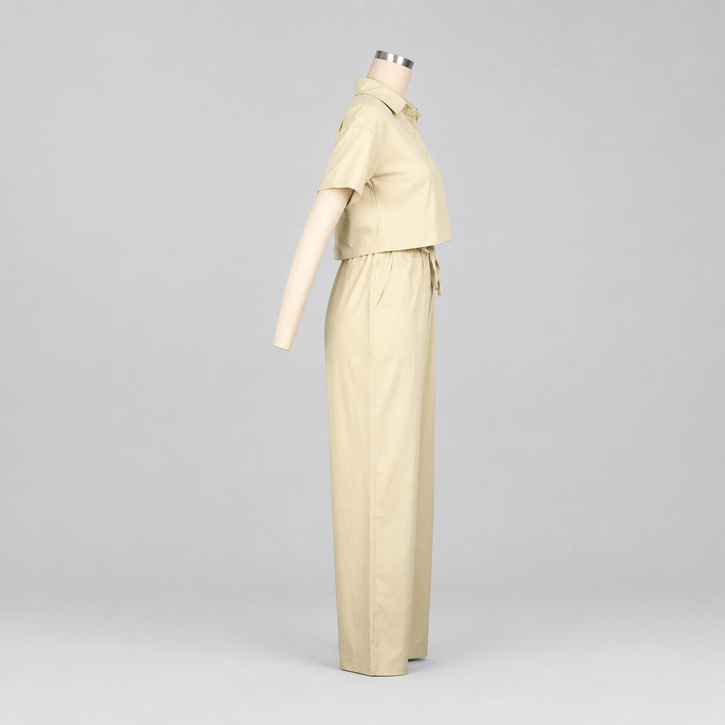 A light beige two-piece outfit displayed on a mannequin, featuring a short-sleeve collared top and matching wide-leg pants, with the brand name CM.YAYA in the top-left corner.