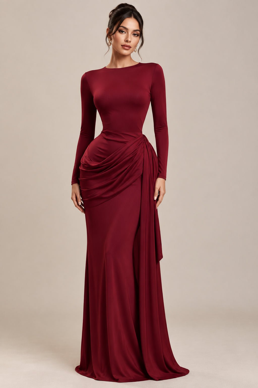 A long-sleeve, high-neck maxi dress in a deep burgundy red, displayed on a mannequin inside a boutique window. The dress features a draped, gathered detail at the waist.
