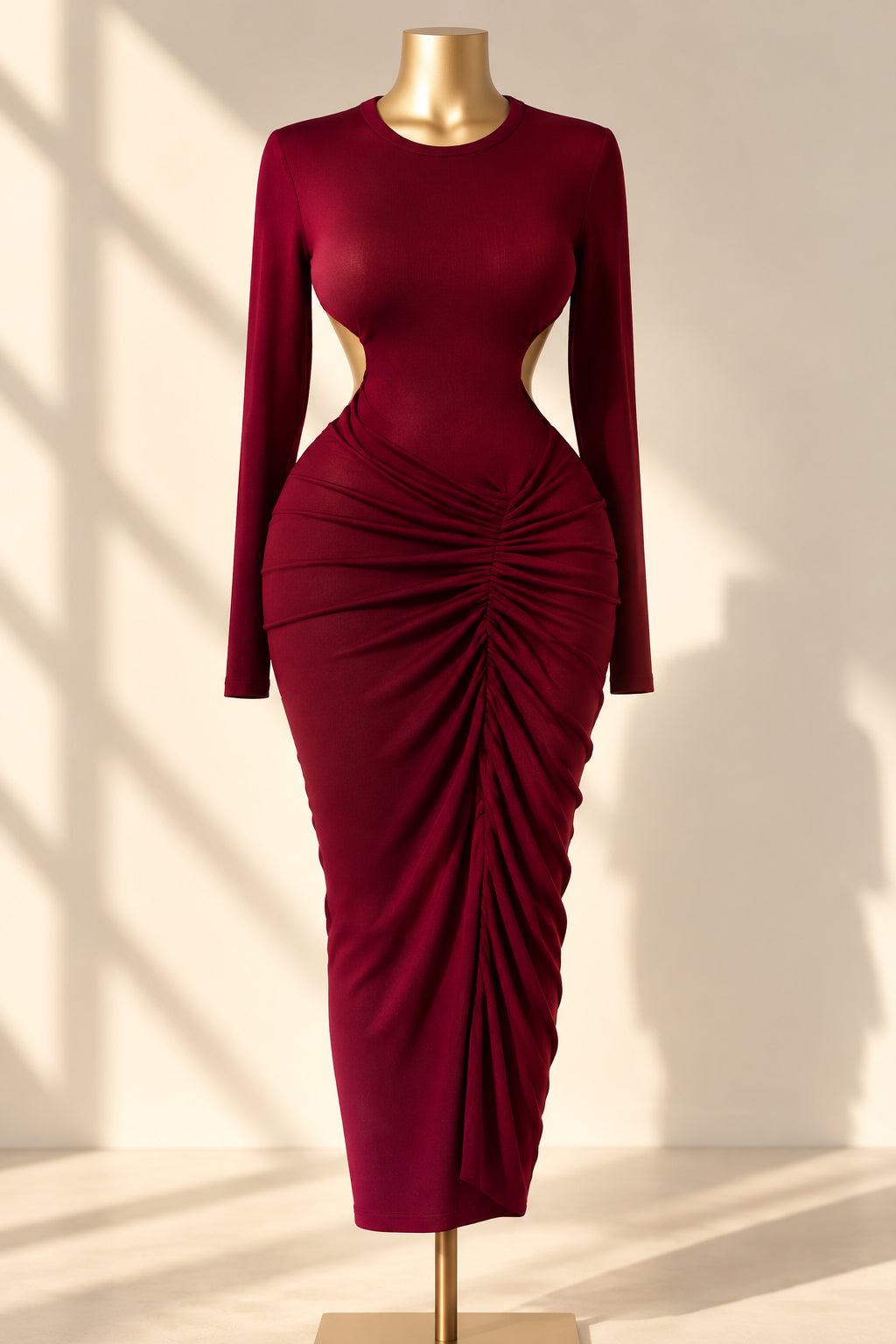 A long-sleeve ribbed knit dress in a deep magenta-pink color, displayed on a gold mannequin torso. The dress features a gathered, ruched design at the waist and a sheer mesh panel on the chest.