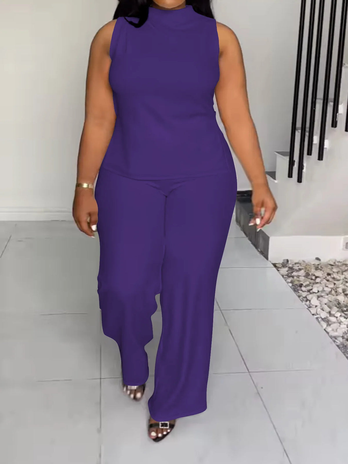 Person wearing a purple jumpsuit standing in a modern indoor setting.