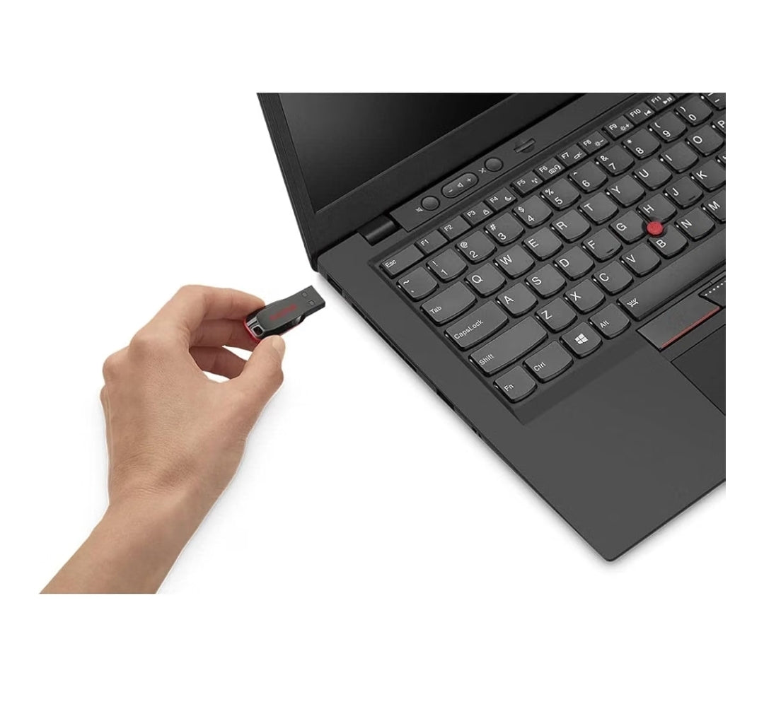 A hand holding a small black and red USB flash drive next to an open black laptop on a white background.